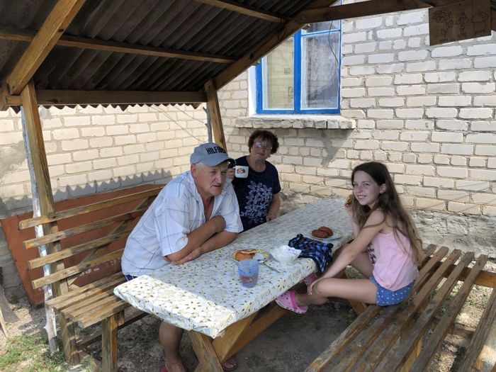 Дедушка и внучки за столом во дворе