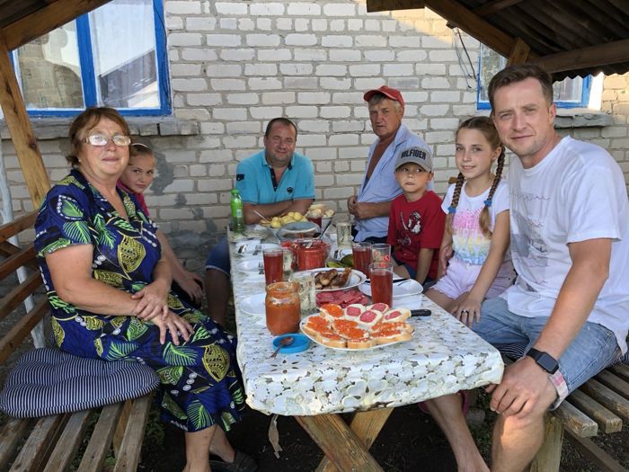 Бабушка и семья за столом под навесом